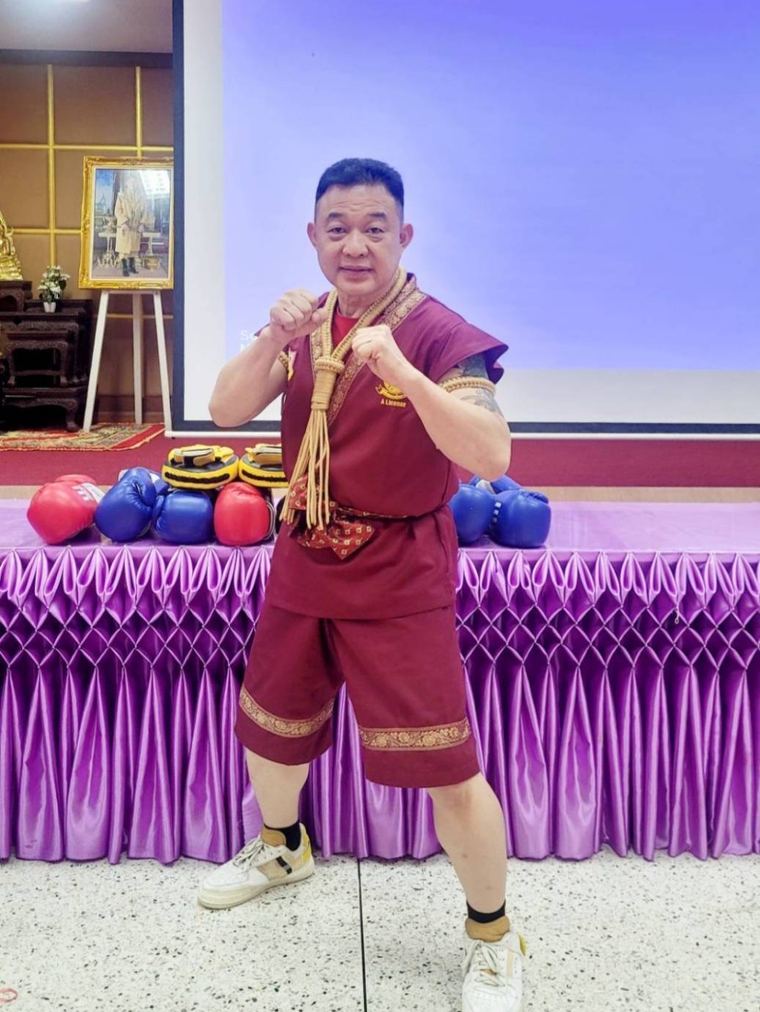 Coach Laemsingh Premchai in traditional muay thai dress, in a fighting stance.