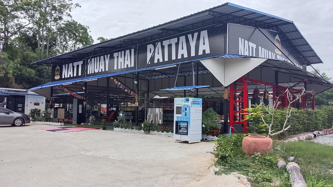 The camp seen from the road: a black steel hall with NATT MUAY THAI PATTAYA in white letters across the roof.
